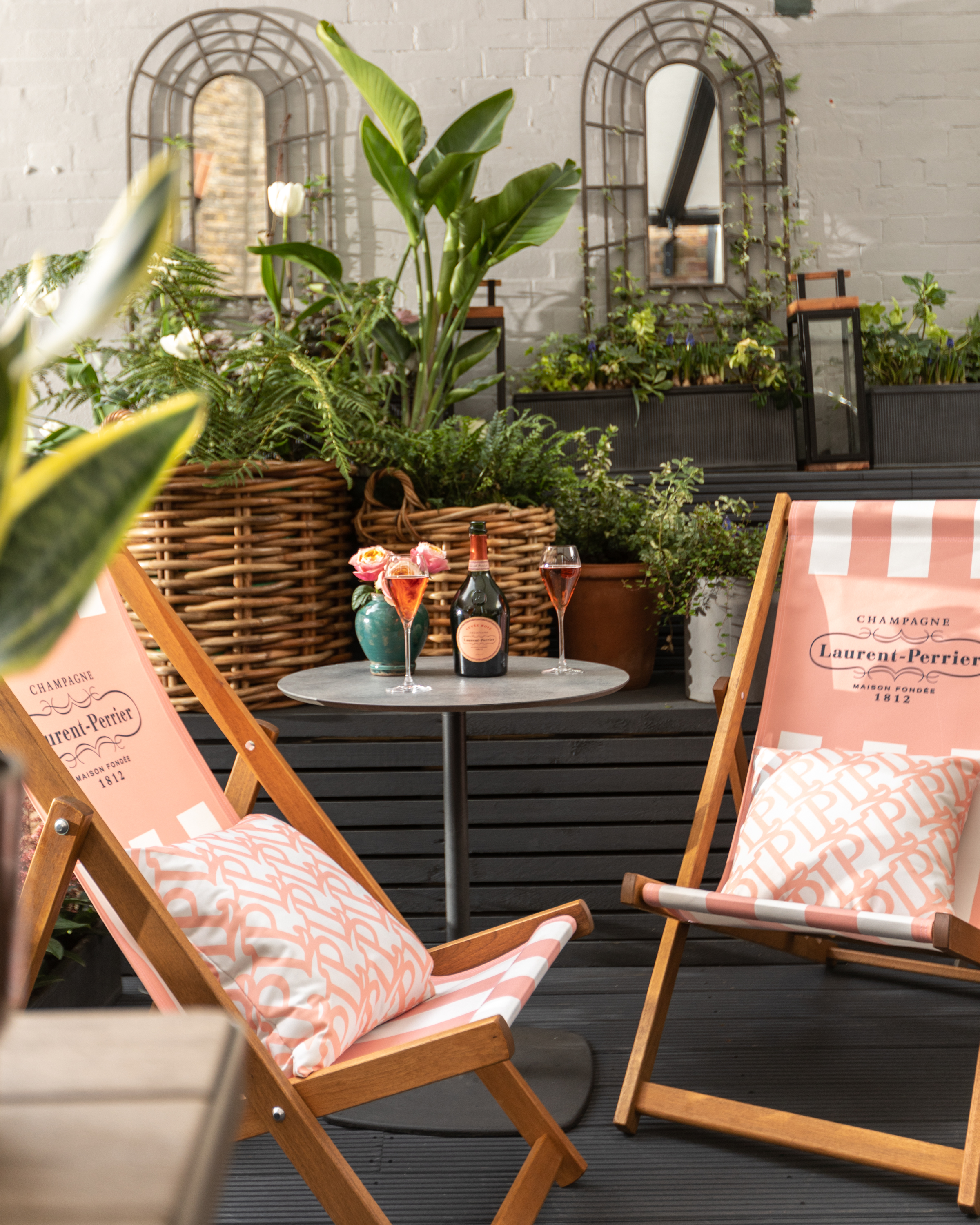 Laurent-Perrier champagne with glasses, pink deck chair and floral arrangement