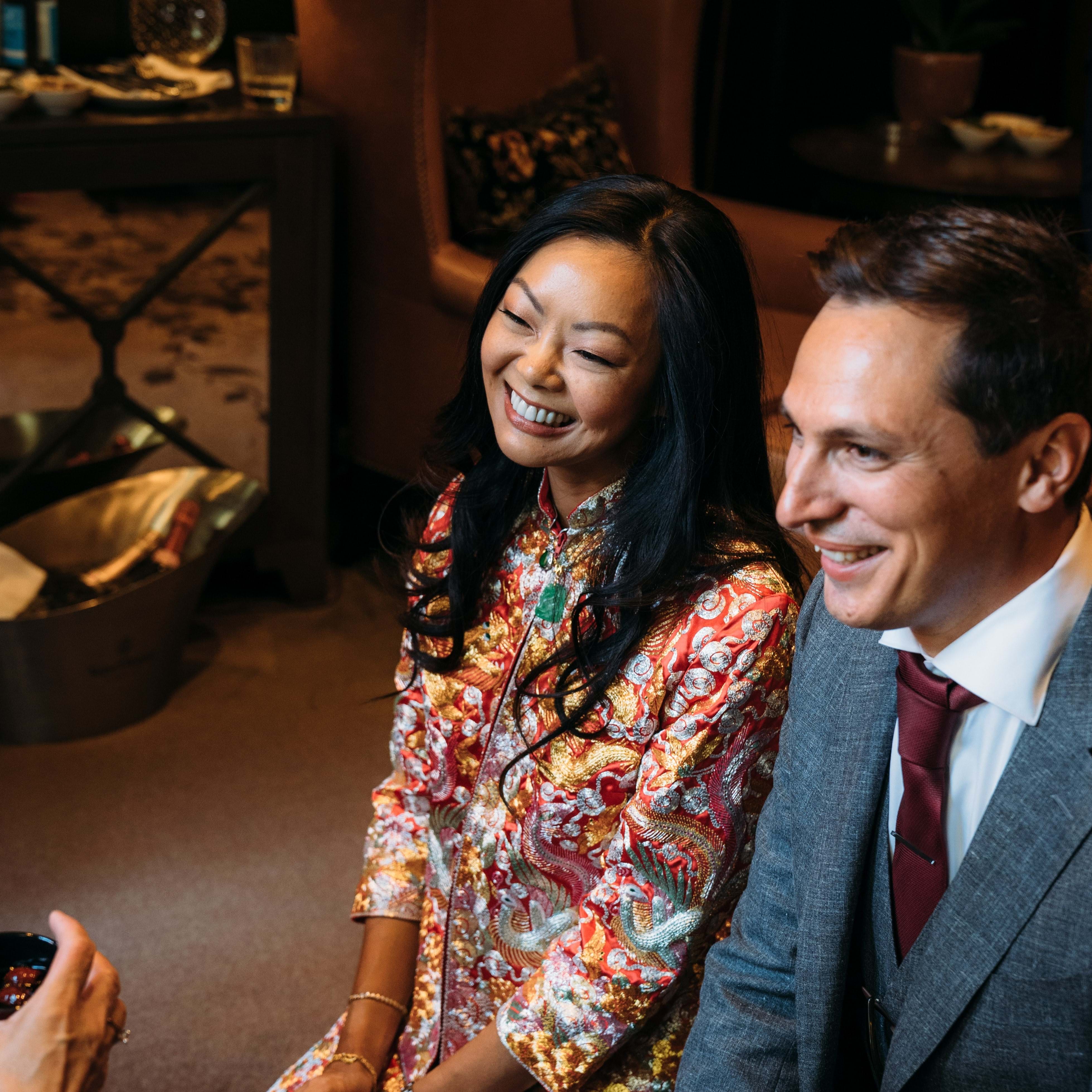Couple sitting together and smiling, dressed in elegant attire