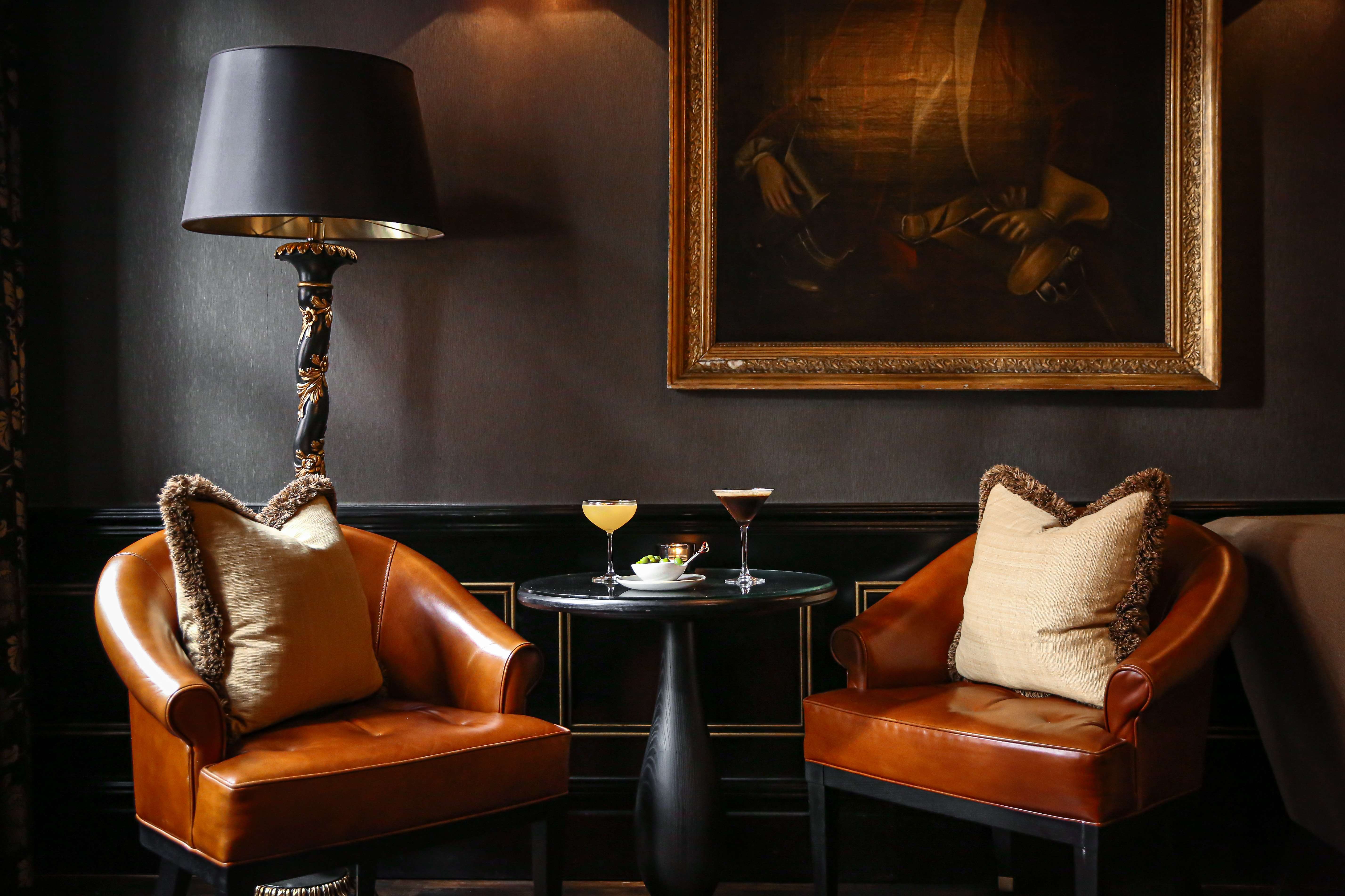 Hotel lounge with leather armchairs, cocktail table and elegant artwork at Chelsea Bar